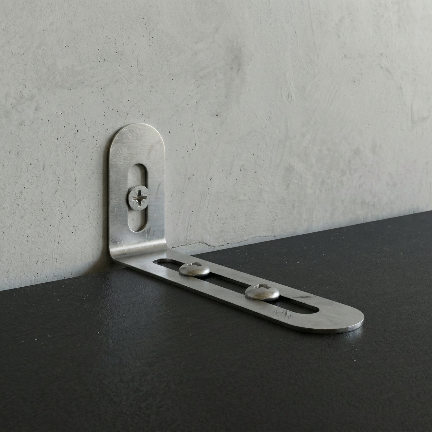 Metal corner bracket on a concrete wall and black surface