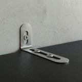 Metal corner bracket on a concrete wall and black surface